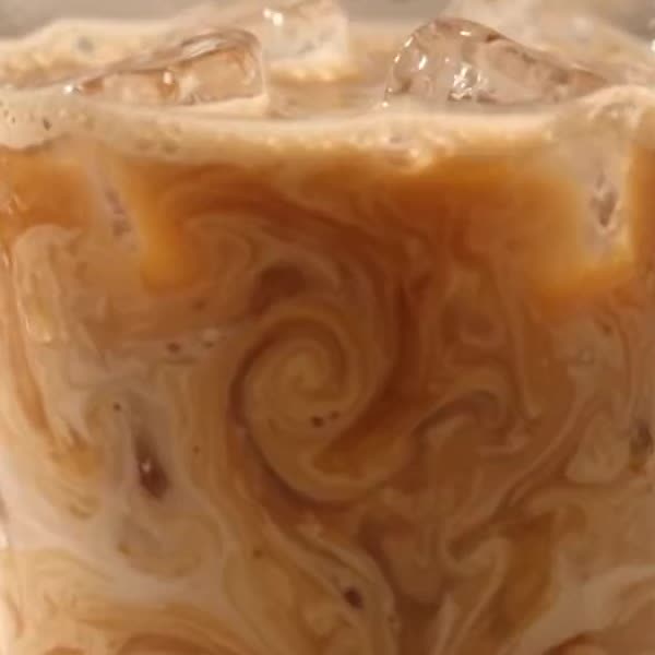 Close up of coffee and milk swirling together around ice