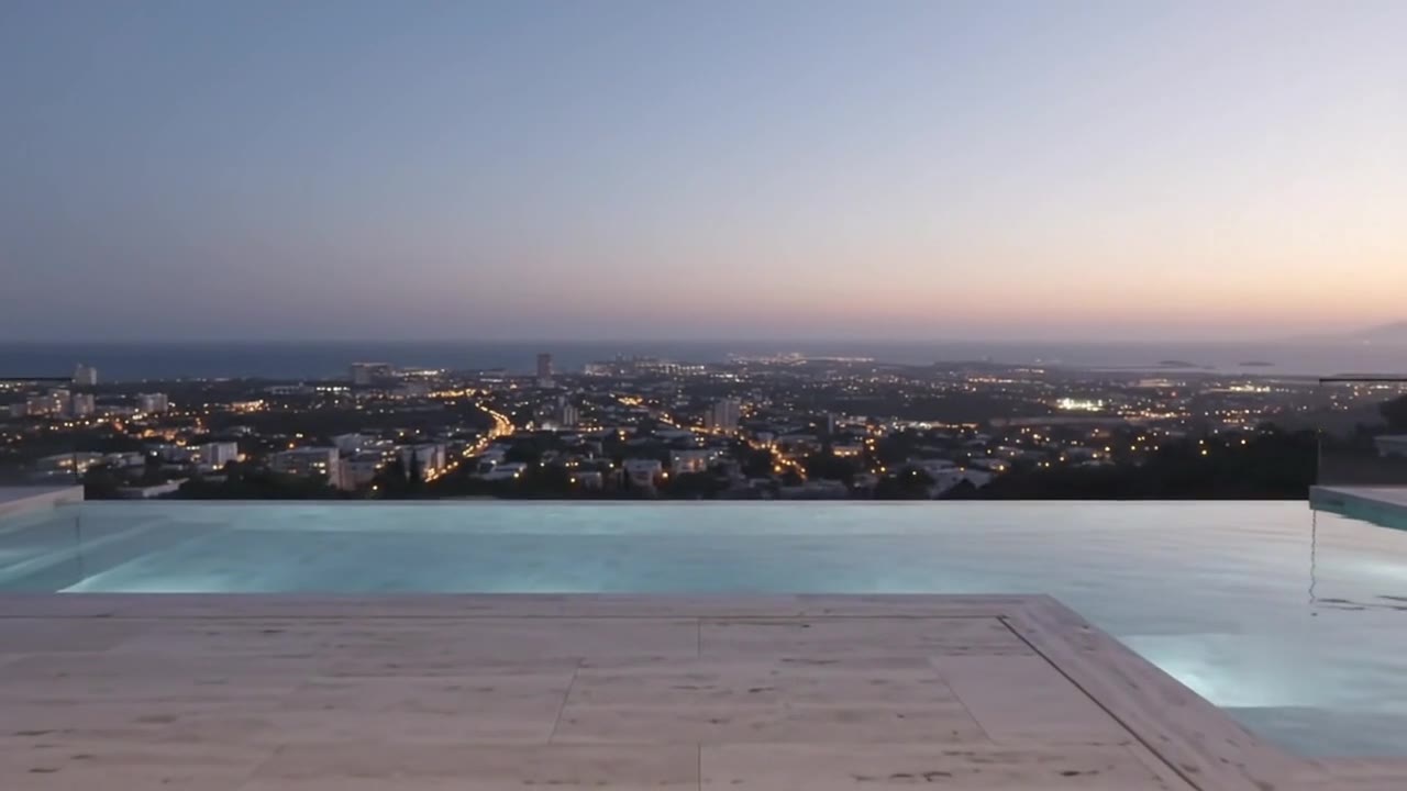 A rooftop terrace with an infinity pool facing the sea at sunset
